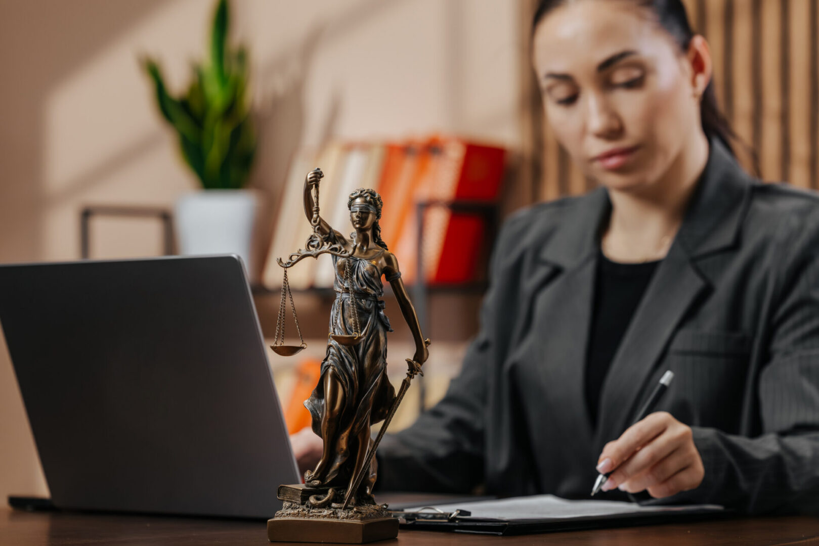 Woman working at desk with Lady Justice statue.