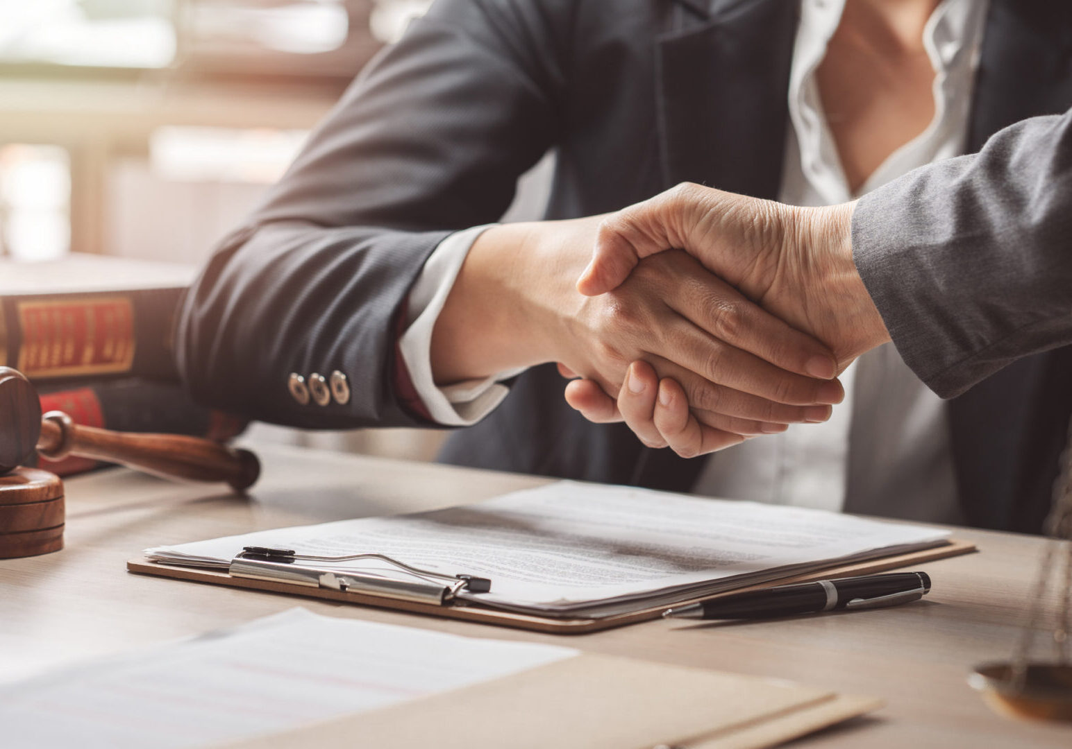 Handshake over legal documents and gavel.